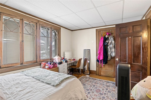 bedroom featuring built in desk, a closet, a drop ceiling, and light hardwood / wood-style flooring