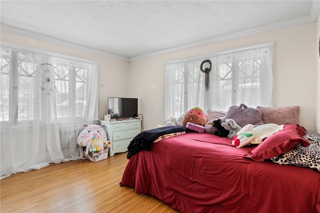 bedroom featuring ornamental molding, wood-type flooring, and multiple windows