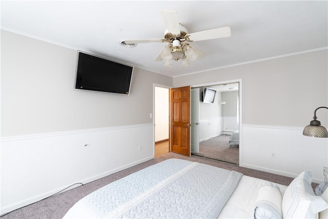 carpeted bedroom featuring ornamental molding, a closet, and ceiling fan