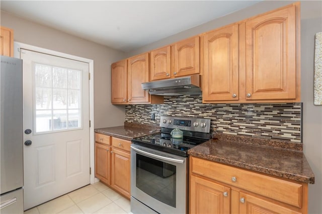 kitchen with stainless steel appliances, backsplash, light tile patterned floors, and dark stone counters