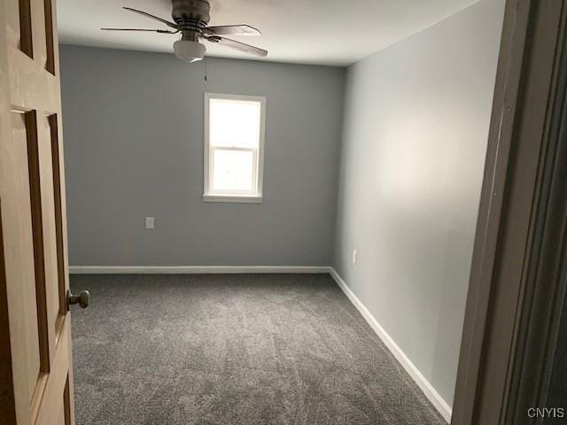 empty room with dark carpet, a ceiling fan, and baseboards