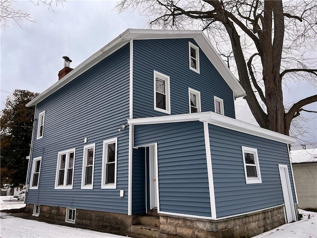 snow covered property with a chimney