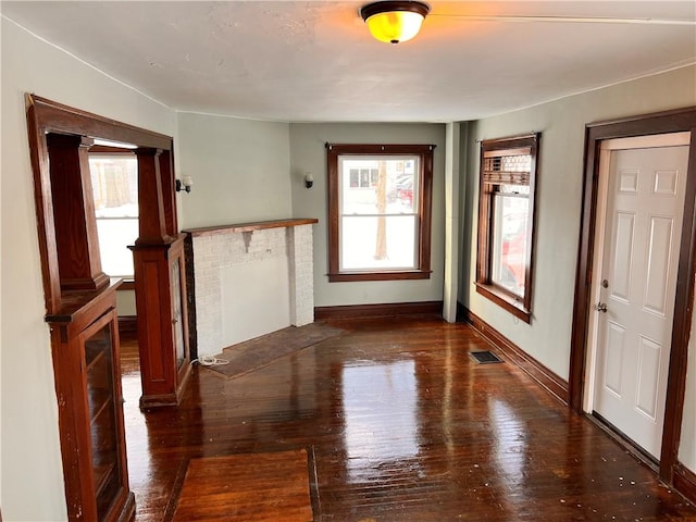 unfurnished living room with dark wood-style floors, baseboards, and visible vents