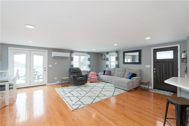 living room featuring light wood-style flooring, recessed lighting, baseboards, a wall mounted AC, and baseboard heating