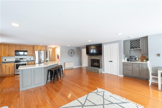 kitchen with a breakfast bar area, stainless steel appliances, open floor plan, light countertops, and a center island