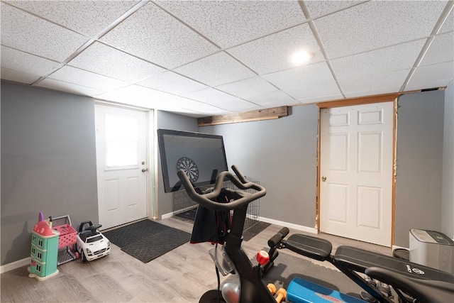 exercise room with a paneled ceiling, baseboards, and wood finished floors