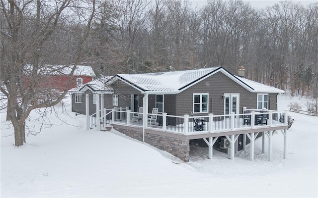 snow covered rear of property with a chimney and a wooden deck