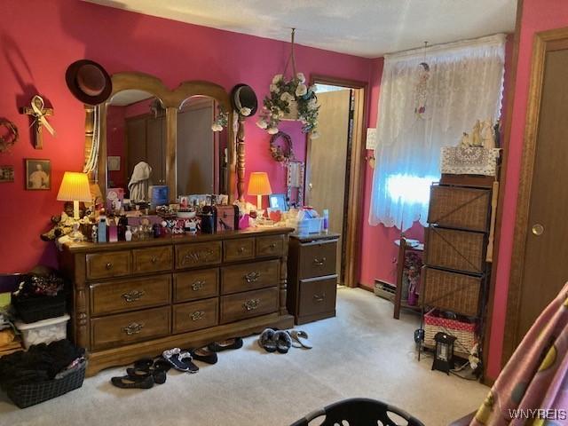 bedroom featuring light carpet and a baseboard heating unit