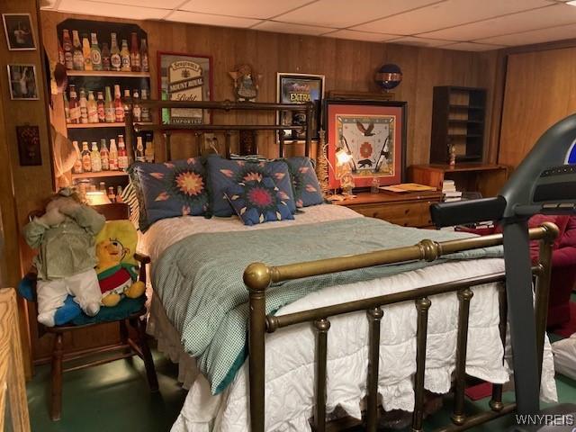 bedroom with wood walls and a paneled ceiling