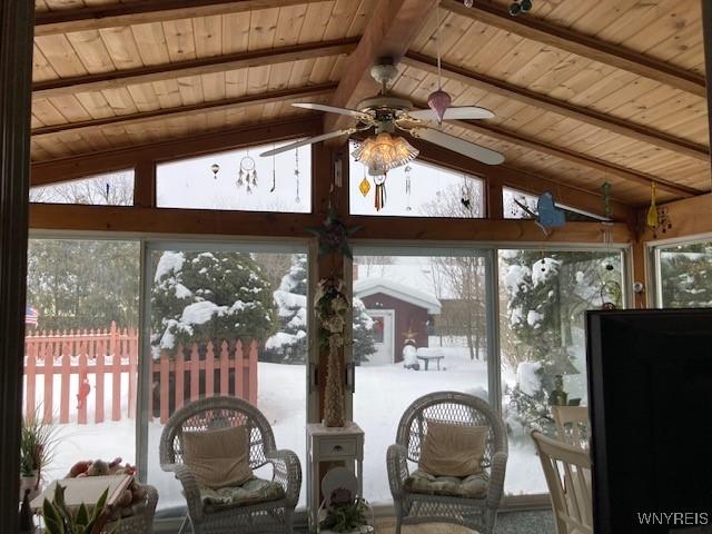 sunroom / solarium featuring lofted ceiling with beams, wooden ceiling, and a ceiling fan