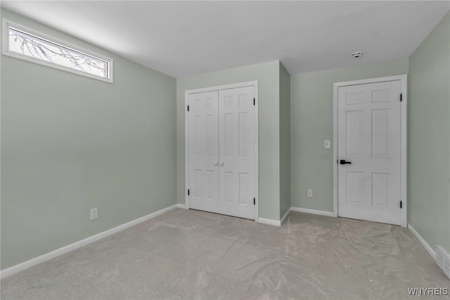 unfurnished bedroom featuring a closet, light colored carpet, and baseboards