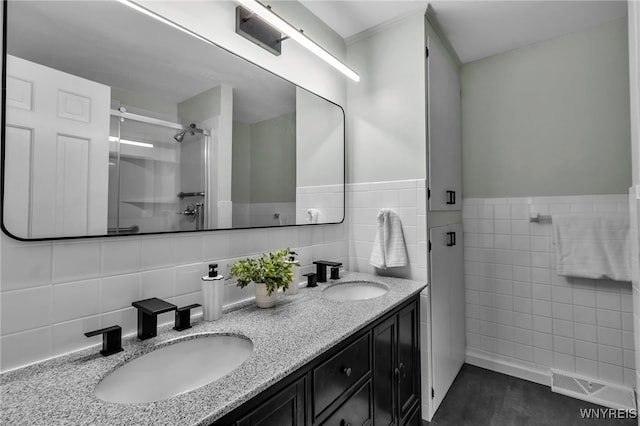 full bathroom with double vanity, a stall shower, a sink, and visible vents