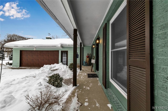 snow covered patio with a garage