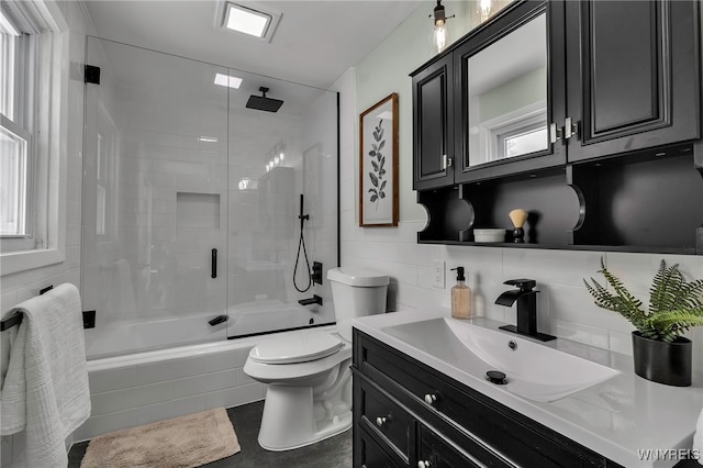 bathroom with toilet, vanity, tile walls, tiled shower / bath, and backsplash