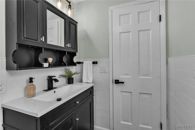 bathroom with wainscoting, vanity, and tile walls