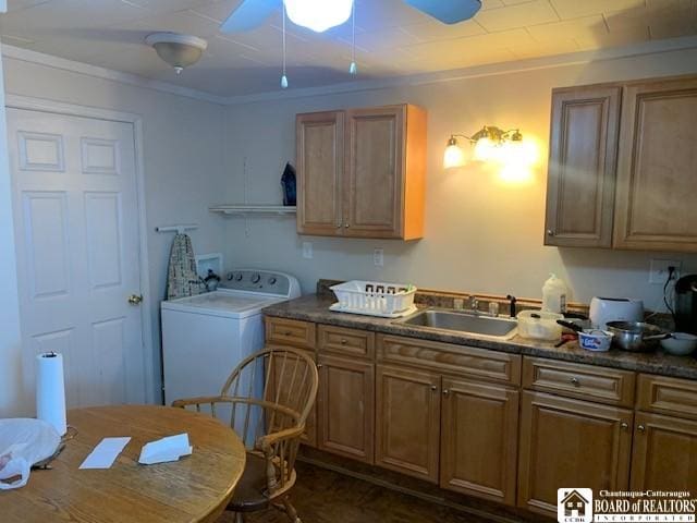 kitchen featuring dark countertops, washer / clothes dryer, brown cabinets, and a sink