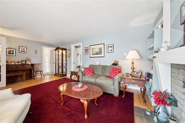 living area featuring a fireplace, wood finished floors, and baseboards