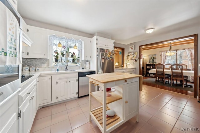 kitchen with stainless steel appliances, pendant lighting, white cabinetry, and a sink