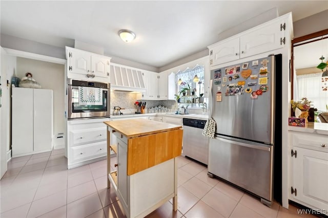 kitchen featuring white cabinets, light tile patterned floors, a kitchen island, and stainless steel appliances