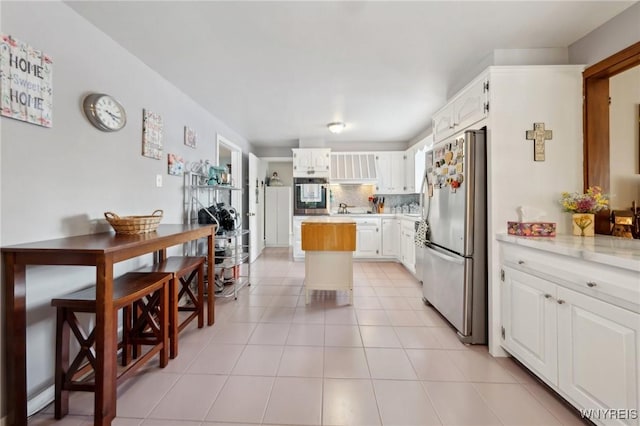 kitchen featuring tasteful backsplash, stainless steel appliances, white cabinetry, wooden counters, and light tile patterned flooring