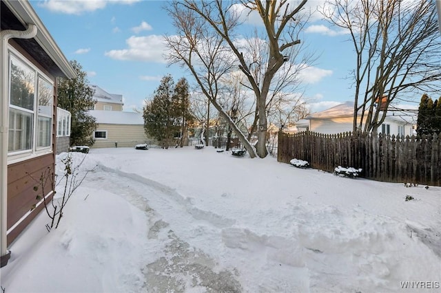 snowy yard featuring fence