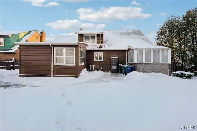 snow covered rear of property featuring fence