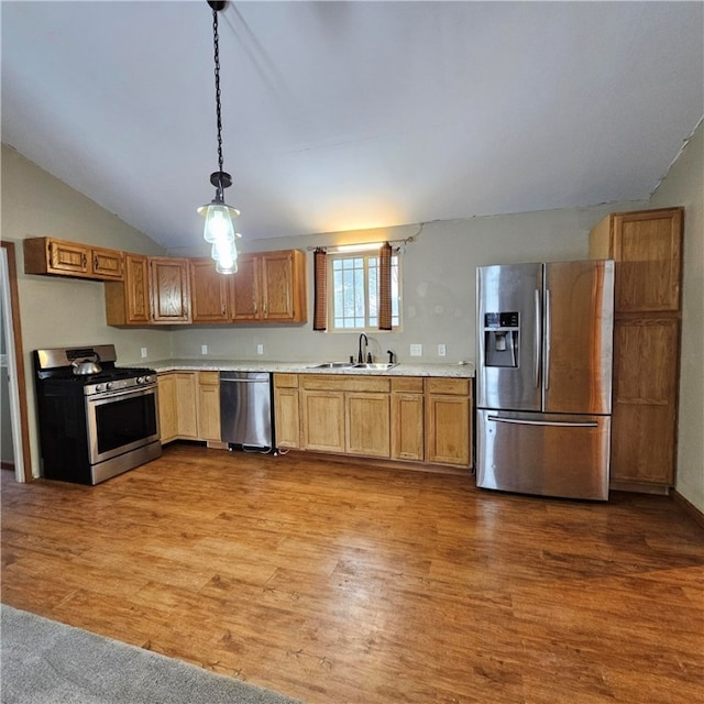 kitchen featuring light countertops, hanging light fixtures, appliances with stainless steel finishes, a sink, and wood finished floors