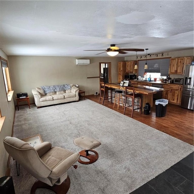 living area featuring a textured ceiling, a ceiling fan, dark wood-style flooring, and an AC wall unit