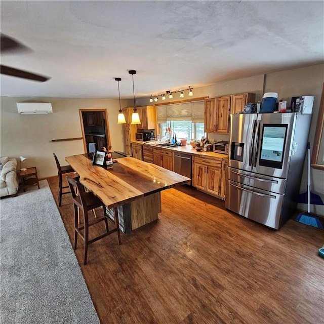 kitchen featuring appliances with stainless steel finishes, dark wood-style flooring, decorative light fixtures, light countertops, and a wall mounted AC