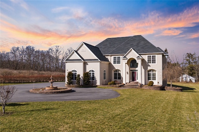 view of front of home featuring curved driveway and a front lawn