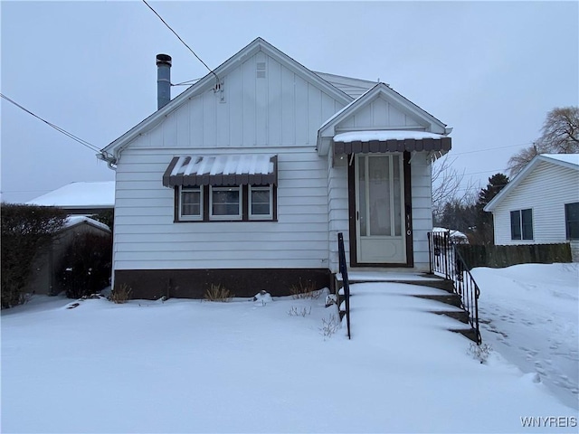 bungalow-style home with a chimney, fence, and board and batten siding