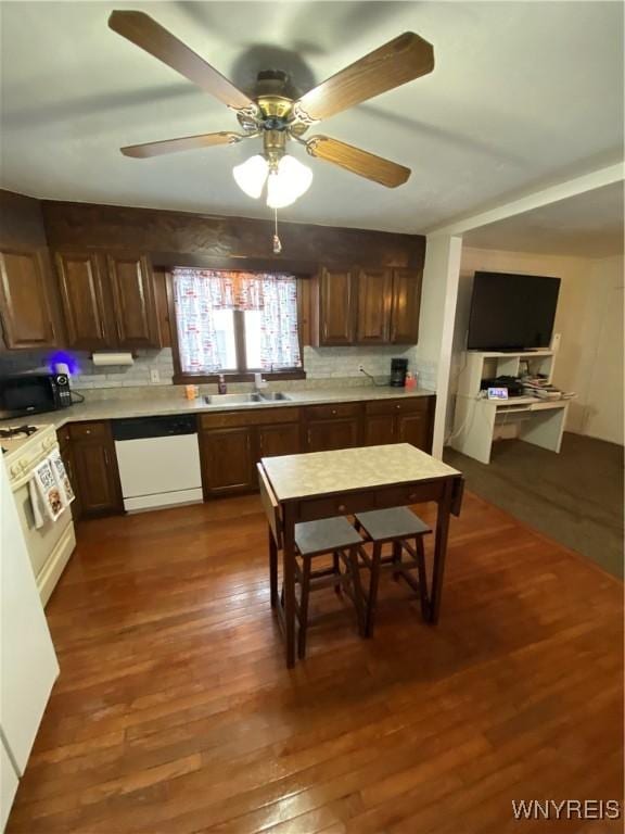 kitchen with black microwave, dark wood-style flooring, a sink, light countertops, and dishwasher