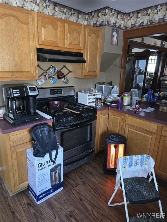 kitchen featuring dark countertops, gas stove, dark wood-style floors, and under cabinet range hood