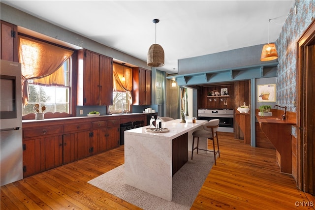 kitchen featuring hanging light fixtures, a breakfast bar area, wood finished floors, and light countertops