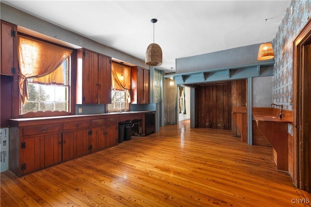 kitchen with a sink, light wood-style flooring, and pendant lighting