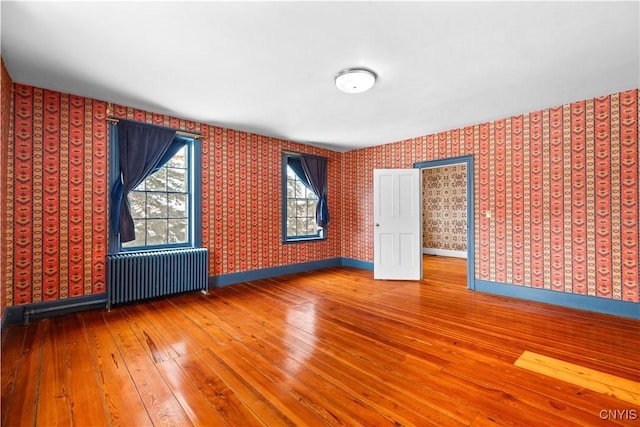 empty room with radiator, baseboards, and wallpapered walls