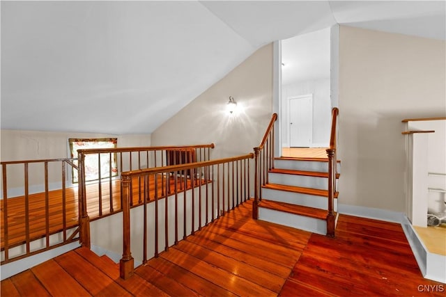 stairway featuring baseboards, vaulted ceiling, and wood finished floors