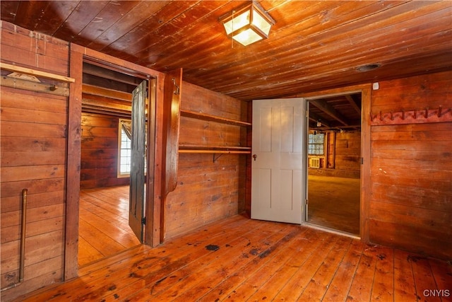 spare room with wood walls, wooden ceiling, and wood finished floors