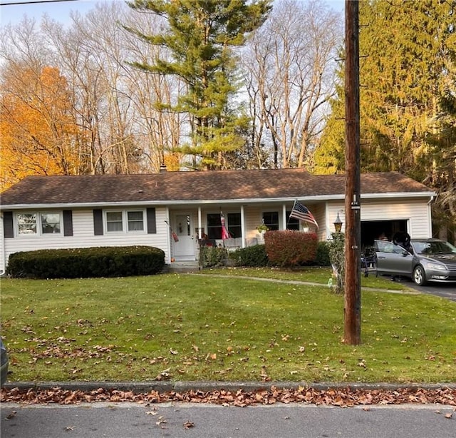 ranch-style home featuring an attached garage, driveway, a chimney, and a front yard