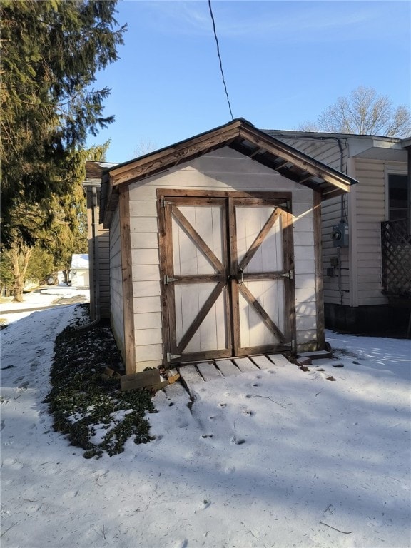 snow covered structure with an outbuilding and a storage unit