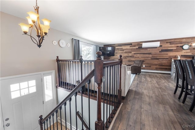 staircase featuring an inviting chandelier, wood finished floors, and wood walls