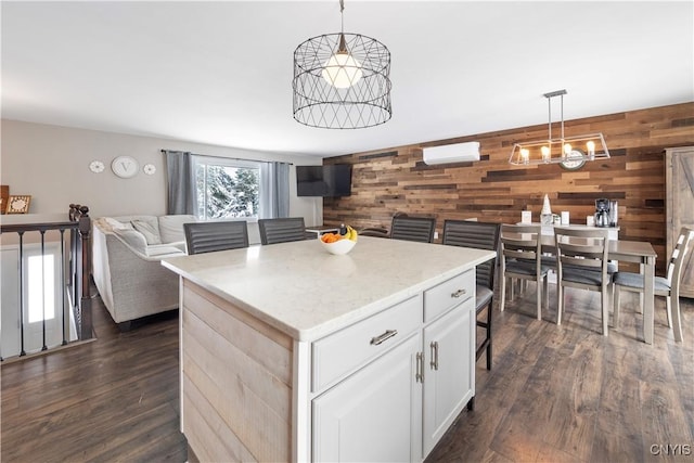 kitchen featuring white cabinets, open floor plan, hanging light fixtures, a wall mounted AC, and a center island