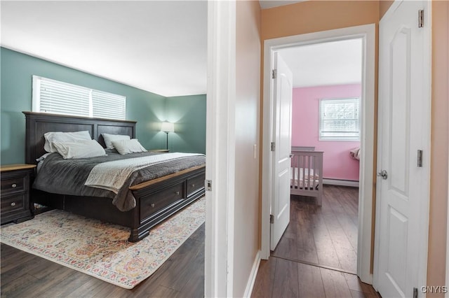 bedroom featuring baseboards, a baseboard heating unit, and dark wood finished floors