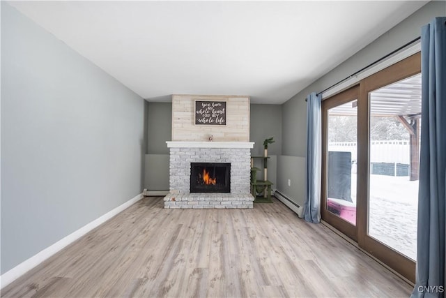 unfurnished living room featuring a brick fireplace, baseboards, baseboard heating, and light wood finished floors