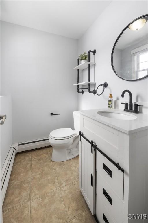 bathroom with toilet, vanity, baseboard heating, and tile patterned floors