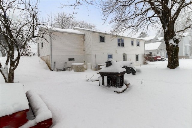 snow covered back of property featuring a garage