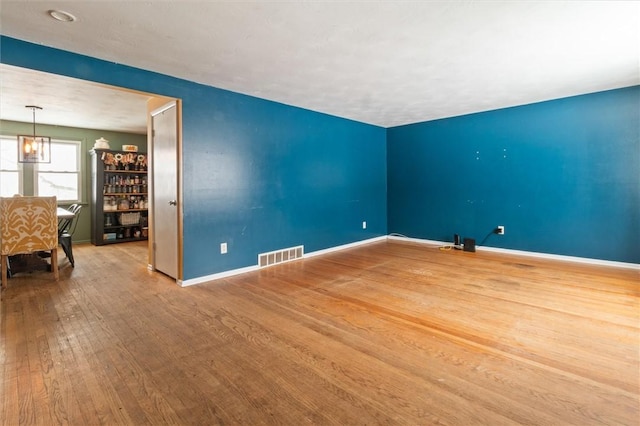 unfurnished room with wood finished floors, visible vents, and baseboards