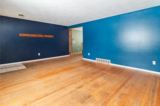 empty room featuring light wood-style flooring, visible vents, and baseboards