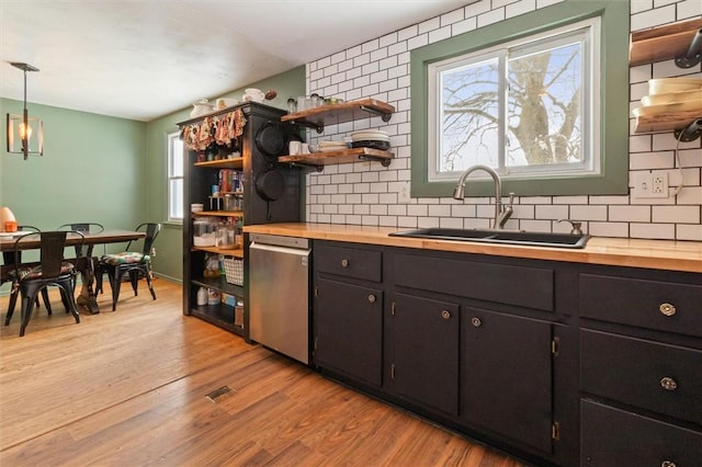 kitchen featuring wood counters, pendant lighting, stainless steel dishwasher, open shelves, and a sink