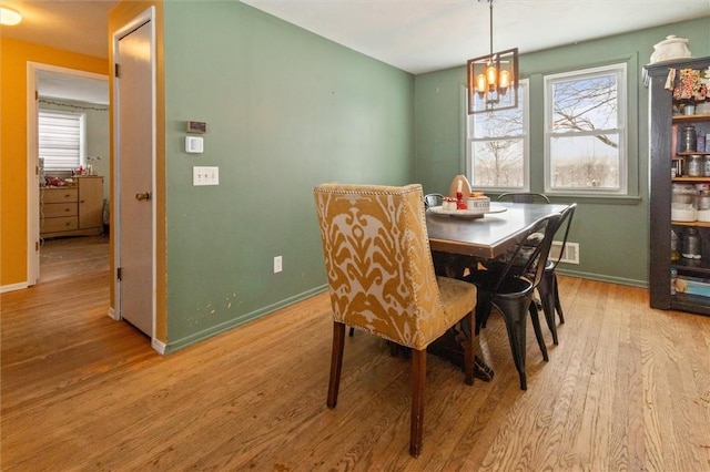 dining area featuring light wood-type flooring, baseboards, and a chandelier